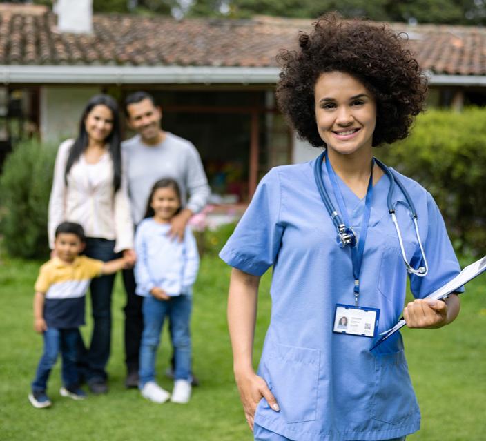 Clinician standing with family in background