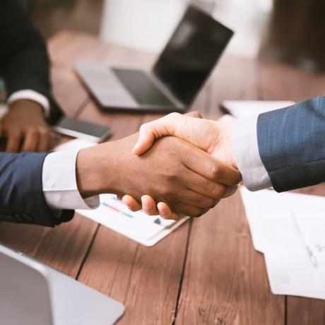 Two people shaking hands across a table